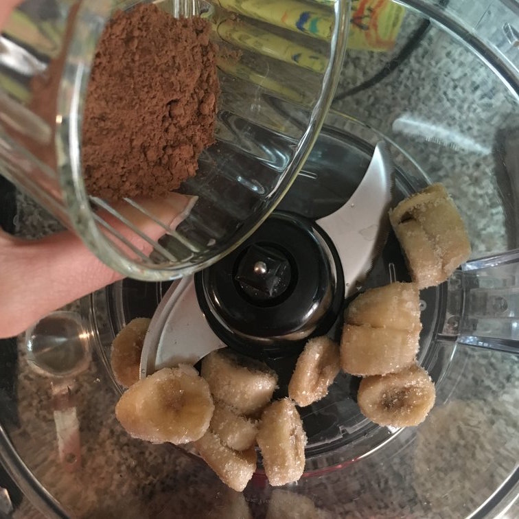 Adding in cacao powder to frozen banana before blending